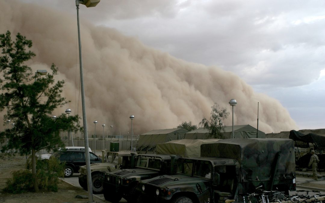 Dust storm with military vehicles in the foreground