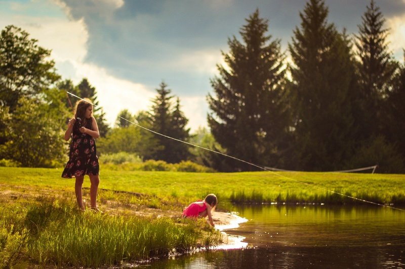A Girl fishing at a pond with a little boy